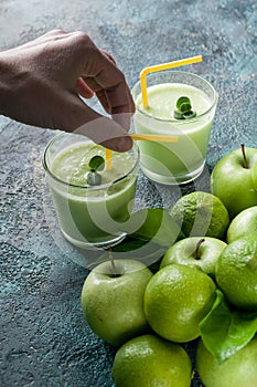 Female hand and smoothies apples and limes on a dark blue concrete background. Detox programm