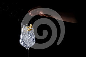 Female hand splashing lemon into the iced water