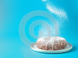 Female hand sprinkling icing sugar on bundt cake