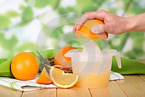 Female hand squeezes an orange by hand juicer