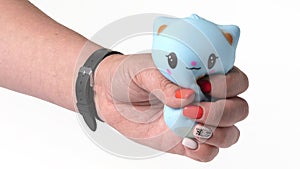 Female hand squeezing anti stress cat toy on white background.