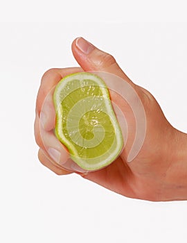 Female hand squeezing a green lemon.