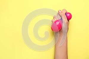 Female hand squeezing stress ball on color background