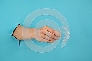 A female hand sticking out of a hole from a blue background holds removable night retainers.