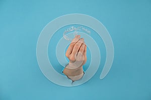 A female hand sticking out of a hole from a blue background holds removable night retainers.
