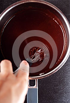Female hand stirring chocolate in stainless steel saucepan