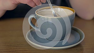 Female hand stirring coffee in a cup