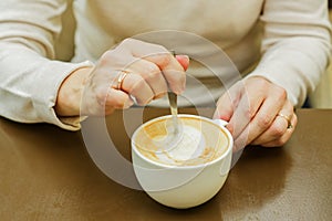 Female hand stirring cup of cooffe. Morning freshly cooked cappuccino photo