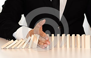Female hand stopping domino effect on grey background