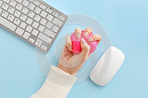 Female hand with stress ball, computer keyboard and mouse on color background