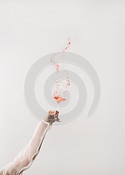 Female hand swirling glass of rose wine making splash