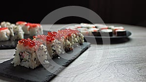 Female hand takes food with chopsticks.Sushi rolls japanese food rotated over black background. California Sushi roll