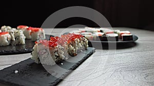 Female hand takes food with chopsticks.Sushi rolls japanese food rotated over black background. California Sushi roll