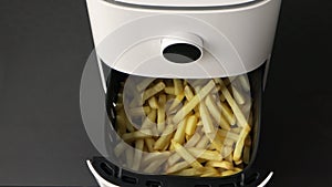 Female hand takes ready french fries cooked in air fryer