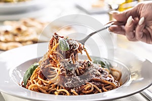 Female hand takes spaghetti pomodoro e basilico with parmesan cheese and basil on a fork