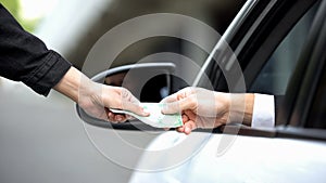 Female hand taking euro banknote from driver hand, autobahn payment, order