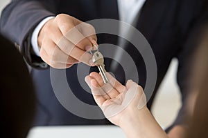 Female hand taking key from realtor buying renting new home