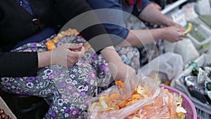 Female hand taking orange peel and skewer it on a needle and thread