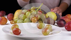Female Hand Taking a Ripe Apple or Peach from a Plate, Bites it and Puts it Back