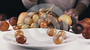 Female Hand Taking a Ripe Apple or Peach from a Plate, Bites it and Puts it Back