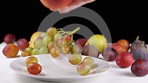 Female Hand Taking a Ripe Apple or Peach from a Plate, Bites it and Puts it Back