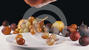 Female Hand Taking a Ripe Apple or Peach from a Plate, Bites it and Puts it Back