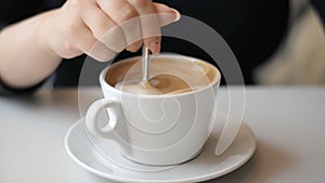 Female hand teaspoon stirring coffee cappuccino