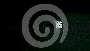 Female hand throwing dice on black background in slow motion. Two standard six-sided pipped dice with rounded corners on