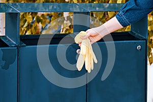 Female hand throws medical gloves in the trash