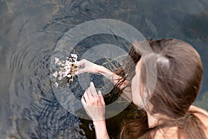 The female hand that touches the blue water. The lake is clean. With a drop of water on the water