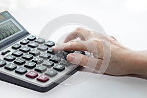 Female hand is touching buttons on the calculator, closed-up and isolated on white background.