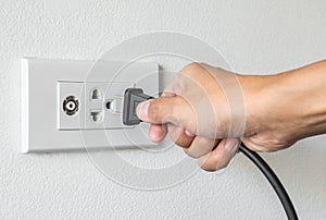 Female hand trying to plugging in appliance to electrical outlet