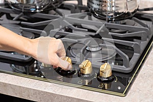 Female hand turn on gas stove