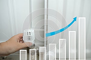 female hand turns valve on heating battery, halogram of growth graph and up arrow, growth in direction of development, concept