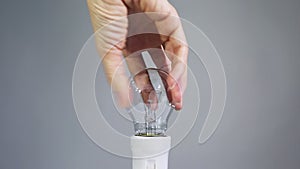 Female hand twists bulb in a cartridge.