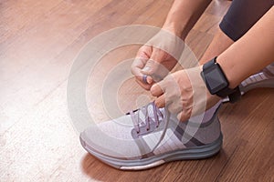 Female hand tying shoelaces wearing watchband