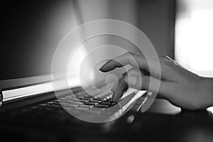 Female hand typing on a laptop keyboard. BW photo