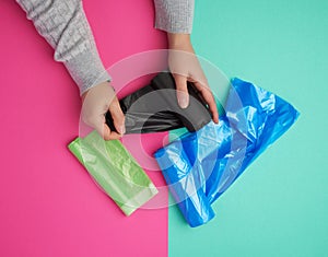 Female hand unwinds a black plastic bag for rubbish