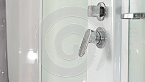 Female hand using bathroom tap in shower cabin. Closeup of a shower knob regulator and his water dispenser. Bathroom tap