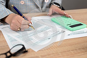 Female hand using calculator for fill 1040 tax form business individual income at office