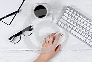 Female hand using computer mouse on organized white desktop