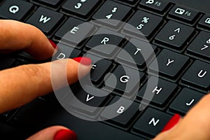 Female hand using pc keyboard. Close up woman hand on computer keyboard on black wooden background