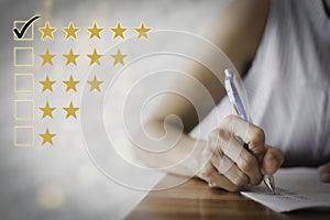 Female hand using a pen to fill out a questionnaire. Customer satisfaction questionnaire. Five star rating. Check the box for five