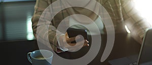 Female hand using smartphone on worktable in office room