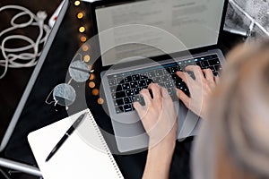 Female hand using touchpad of laptop. Black desk with sunglasses, pen and notebook.