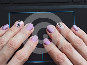 Female hand is using a touchpad on a laptop close up. Creative manicure on the theme of coronavirus