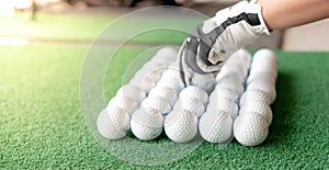 Female hand wearing white professional gloves with the left hand put golfball and preparing to the golf player hitting on the