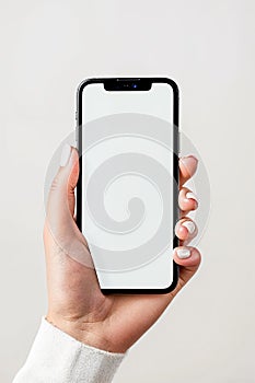 Female hand with white nails holding phone with white blank screen template on a white background.