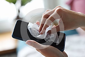 Female hand wipes smartphone with disinfectant napkin from bacteria photo
