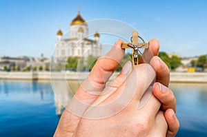 Female hand with wooden cross and orthodox Cathedral